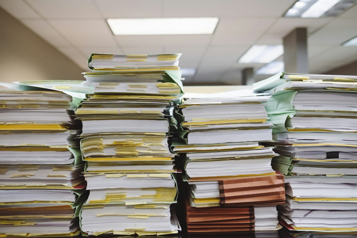 Four stacks of papers in manila folders. Tabs of yellow are seen in many of them.