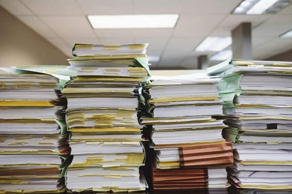 Four stacks of papers in manila folders. Tabs of yellow are seen in many of them.